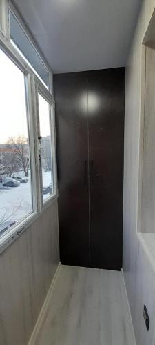 eine schwarze Tür in einem Zimmer mit Fenster in der Unterkunft Квартира in Almaty