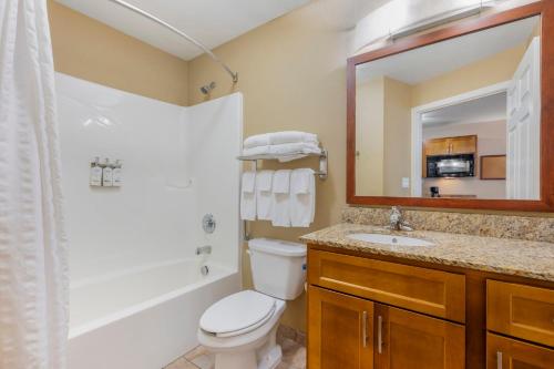 a bathroom with a toilet and a sink and a mirror at Candlewood Suites Indianapolis East by IHG in Indianapolis