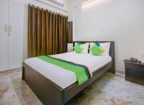a bedroom with a large bed with green pillows at The Trinitywood Hotel & Restaurant in Bangalore
