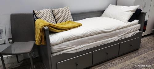 un letto con una coperta gialla e una sedia di London gateway studio flat a Borehamwood