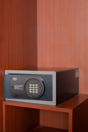 a microwave sitting on top of a wooden shelf at The Capital Hotel Surabaya in Surabaya