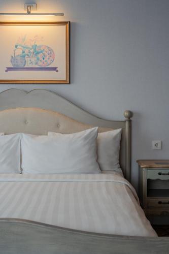 a bedroom with a white bed with a picture on the wall at The Capital Hotel Surabaya in Surabaya