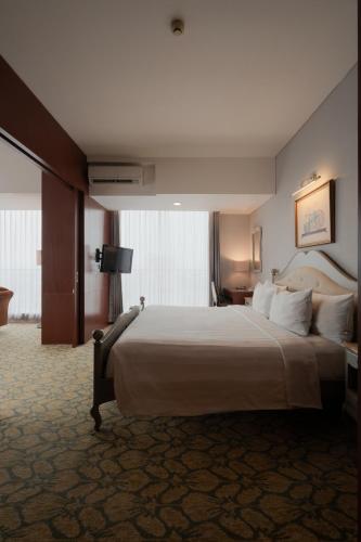 a bedroom with a large bed in a hotel room at The Capital Hotel Surabaya in Surabaya