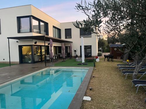 una casa con piscina frente a una casa en LA CASA DE LA OLIVERA Luxurious house, en Les tres Cales