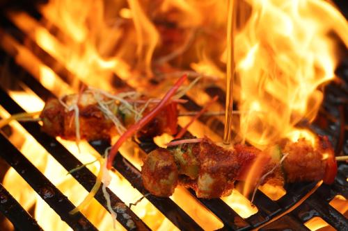 a group of food cooking on a grill with flames at Holiday Inn Agra MG Road an IHG Hotel in Agra