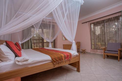 een slaapkamer met een bed met gordijnen en een stoel bij SILVER OAKS HOTEL Boma in Fort Portal