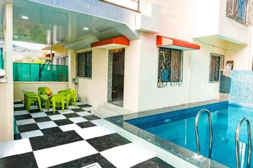 a swimming pool in a house with green chairs at THE PERFECT STAYS: MOUNTAIN MANOR VILLA in Lonavala