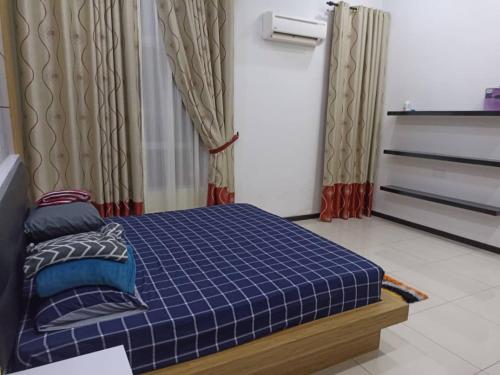 een slaapkamer met een blauw geruit bed en gordijnen bij MELUR HOMESTAY in Jitra