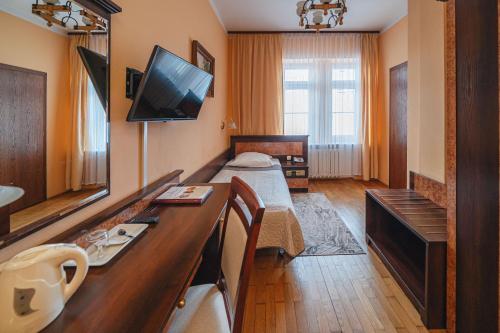a hotel room with a bed and a desk with a television at Zespół Dolina Białego - Willa Pan Tadeusz in Zakopane