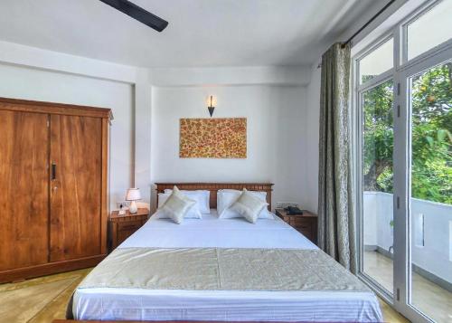 a bedroom with a bed and a large window at Kerawalapitiya Resort in Mahabage