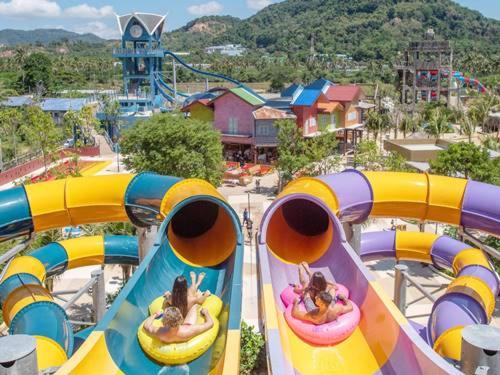 dos chicas montadas en una montaña rusa en un parque en Seaside Haven Karon, en Ka Rorn