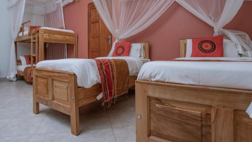 a bedroom with two beds with red pillows at SILVER OAKS HOTEL Boma in Fort Portal