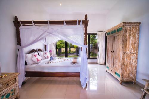 a bedroom with a canopy bed and a large window at Sing Sing Resort Lovina in Lovina