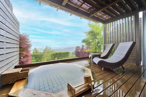 a hot tub on a deck with two chairs and a window at Hotel Grand Bach Atami Crescendo in Atami