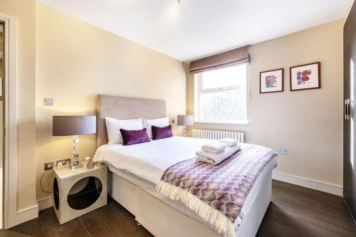 sypialnia z dużym łóżkiem z fioletowymi poduszkami w obiekcie London Suites 2-Hosted by Sweetstay w Londynie
