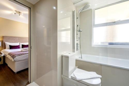 a bathroom with a shower and a tub and a bed at London Suites 2-Hosted by Sweetstay in London