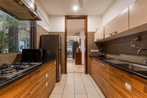 a kitchen with wooden cabinets and a stainless steel refrigerator at Aster by Hireavilla - 3BR w Private pool in Parra in Parra
