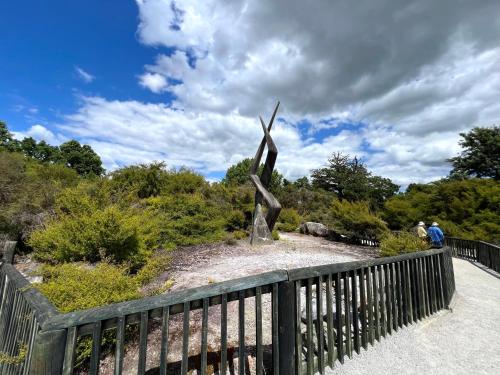 a metal statue on a bridge next to a fence at Parkview Holiday Homes "Opposite of Famous Kuirau Park" in Rotorua