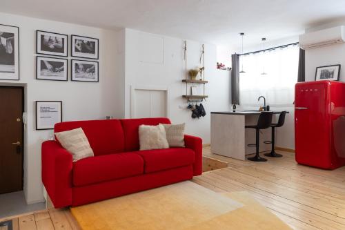 sala de estar con sofá rojo y cocina en Appartamento Loft Sandy, en Milán