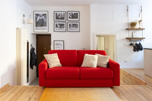 un sofá rojo en una sala de estar con fotos en la pared en Appartamento Loft Sandy, en Milán