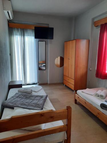 a bedroom with two beds and a wooden cabinet at CHRISTOS Apartments in Paralia Panteleimonos
