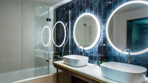 a bathroom with three mirrors and a sink at Crowne Plaza - Nice - Grand Arenas by IHG in Nice