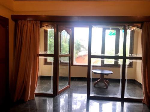 a room with glass doors and a stool and a table at Sea Breeze Beach Resort in Mahabalipuram