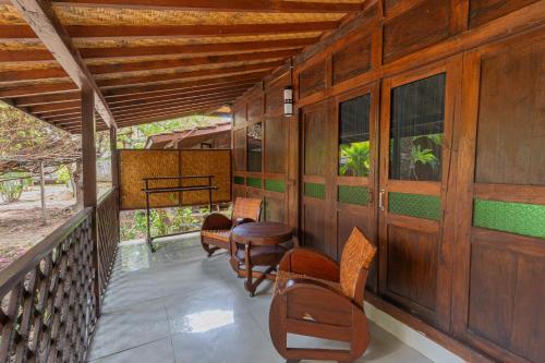 a porch of a house with chairs and tables at Omah Gili Hotel in Gili Air
