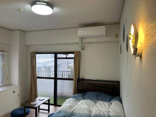 ein Schlafzimmer mit Bett und Blick auf einen Balkon in der Unterkunft North River 601 Peace Wing 6A in Kami-nagarekawachō
