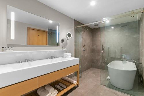 a bathroom with a sink and a tub and a mirror at SA Carbon Beach Suites in Malibu