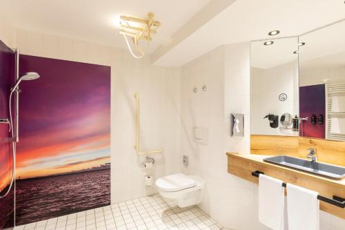 a bathroom with a sink toilet and a painting on the wall at Mercure Hotel Bad Oeynhausen City in Bad Oeynhausen