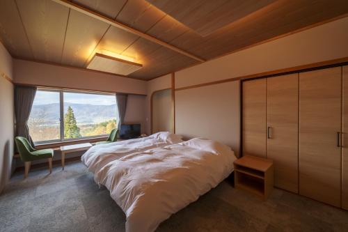 - une chambre avec un grand lit et une grande fenêtre dans l'établissement HOKURYUKO HOTEL North NAGANO, à Iiyama