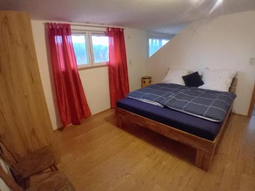 a bedroom with a bed with blue sheets and red curtains at Musik und Natur - Balboo - Bayrischer Wald - Sauna - Pool - Grillen in Spiegelau