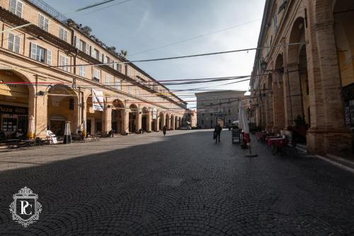 an empty street with buildings and a person walking down the street at Palazzo Capparucci - Dimora storica in Fermo