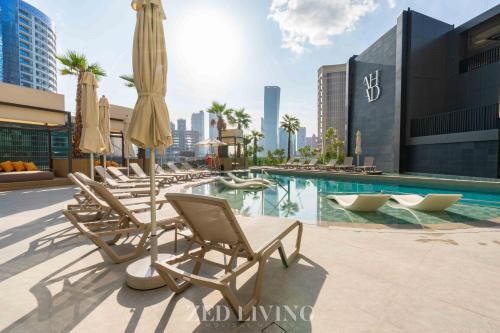 a pool with lounge chairs and umbrellas on a building at Zed Living - Ahad Residences - Tranquil 1 BR in Business Bay in Dubai