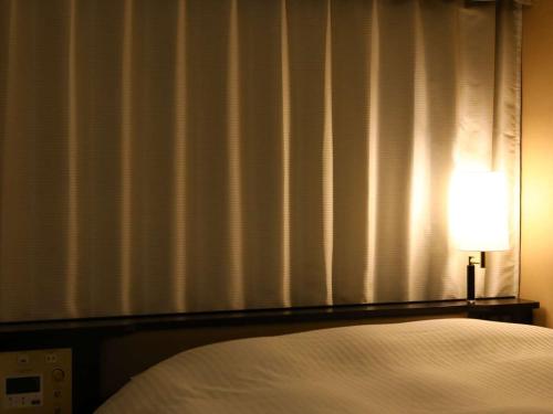- une chambre avec un lit et une lampe à côté d'une fenêtre dans l'établissement APA Hotel Tottori Ekimae Minami -OLD APA Hotel Tottori Ekimae-, à Tottori