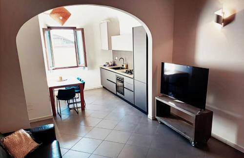 a living room with a kitchen with a table and a television at Lucky House Pisa in Cascina