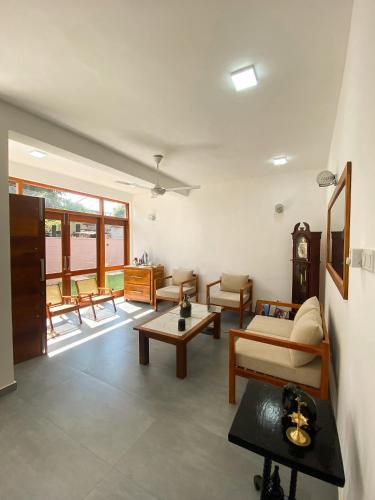 a living room with couches and tables and a clock at THE DOCTORS VILLA in Ragama