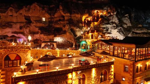 Eine Stadt leuchtet nachts vor einem Berg in der Unterkunft Cappadocia Nar Cave House & Swimming Pool in Nevşehir