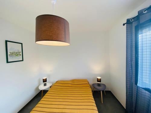 a bedroom with a bed and two tables and a lamp at "Villa Verde "au coeur de Ghisonaccia in Ghisonaccia