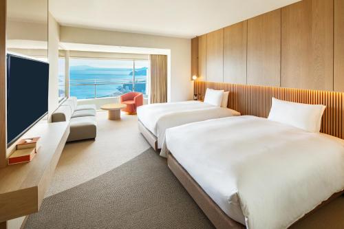a hotel room with two beds and a flat screen tv at Hotel Grand Bach Atami Crescendo in Atami