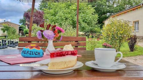 una mesa con una rebanada de pastel y una taza de café en Ferienlandhof Mistorf, 