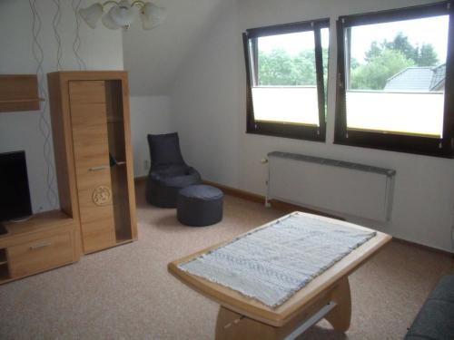 sala de estar con mesa, silla y ventanas en Ferienhof Augustenruh, 