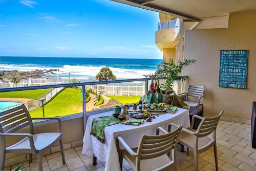 a table on a balcony with a view of the ocean at Sands Beach Breaks Luxury Beach Front Ballito in Ballito