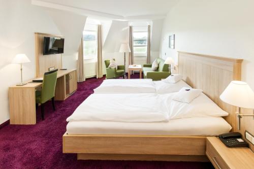 a hotel room with two beds and a desk at Landhotel Buller in Hagen