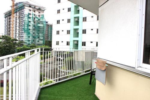 d'un balcon avec de l'herbe verte et une balustrade blanche. dans l'établissement 1 Bedroom Deluxe in Parañaque, à Manille