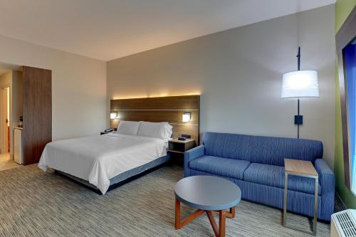 a hotel room with a bed and a blue couch at Holiday Inn Express Campbellsville by IHG in Campbellsville