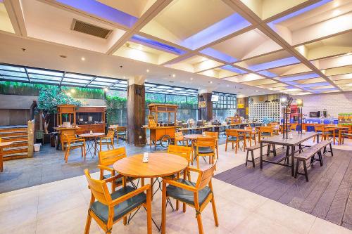 a restaurant with wooden tables and chairs and windows at THE 1O1 Bandung Dago in Bandung