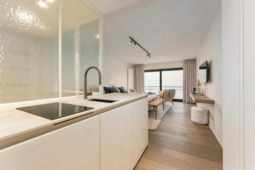 eine Küche mit einem Waschbecken und ein Wohnzimmer in der Unterkunft Seaflower - Romantische luxe studio met zeezicht in De Panne