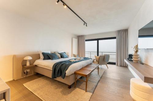 een slaapkamer met een bed en een groot raam bij Seaflower - Romantische luxe studio met zeezicht in De Panne